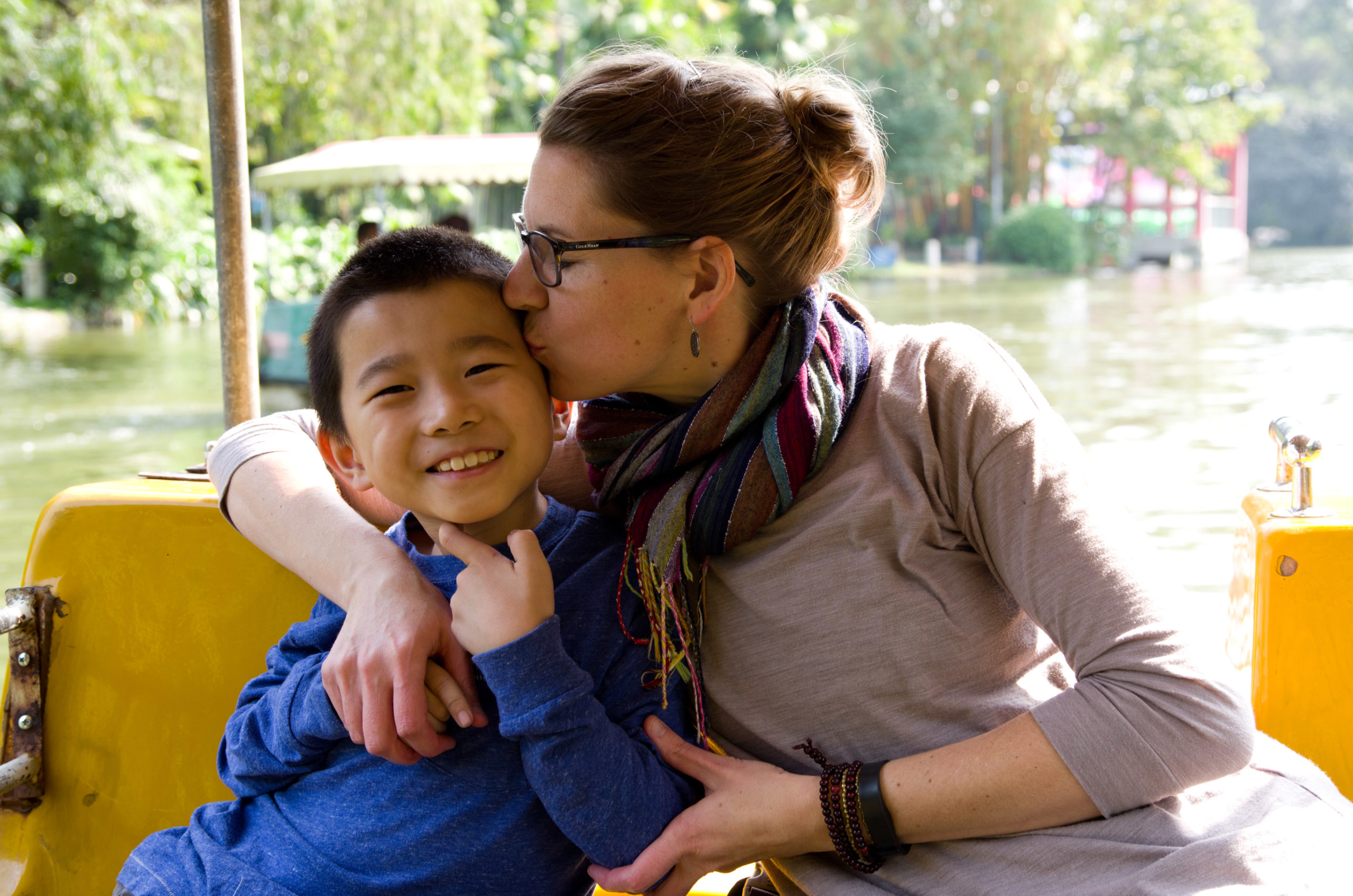 women with her arm around adopted son giving him a kiss on the cheek