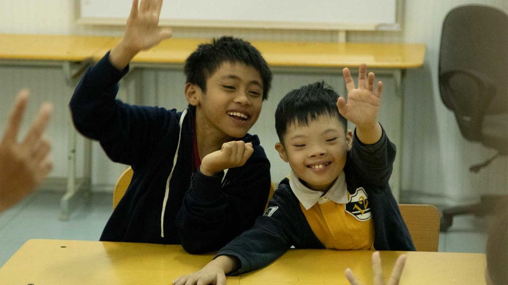 two boys waiving at camera