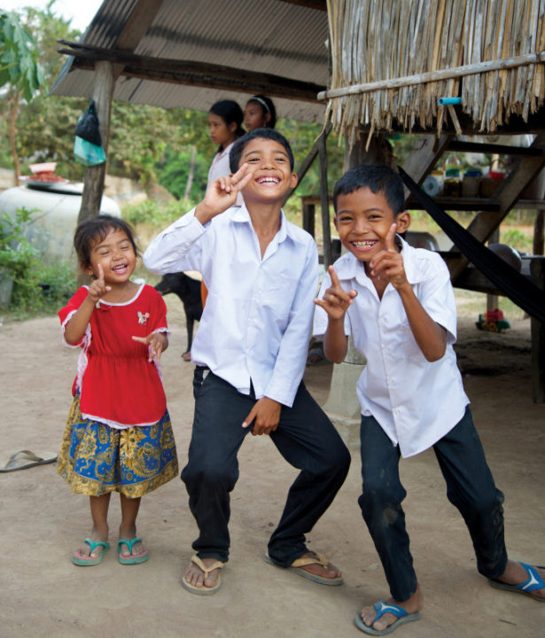 Three of Phanny’s children pose and giggle for Holt’s photographer outside their home.