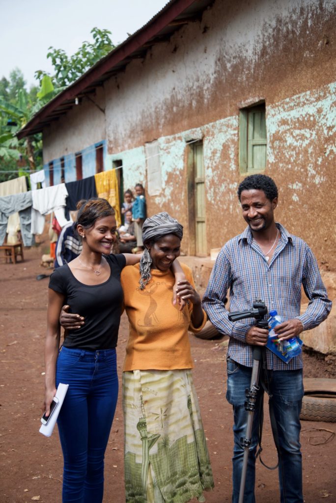 Gelila, Holt's sponsorship coordinator, stands with her arm around one of the women who received a cow to help support her children. The OVC coordinator stands on the other side of her. 