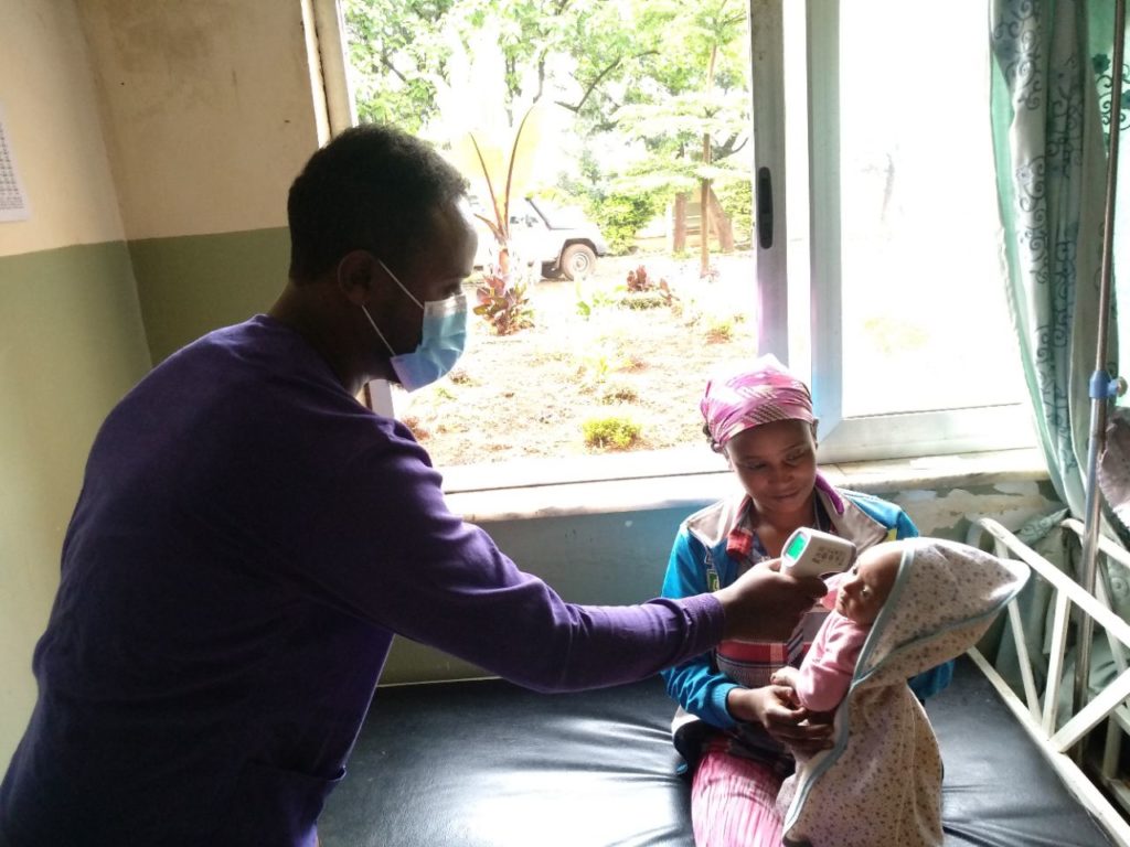 doctor in mask checking a baby's temperature