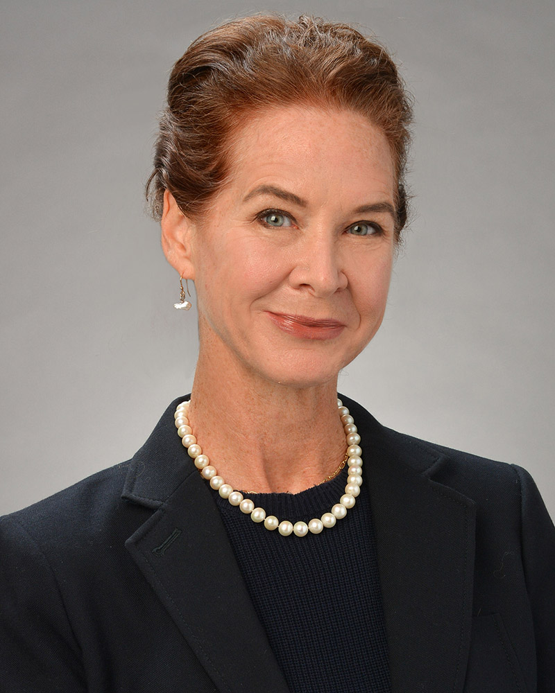 professional headshot of woman with hair up and pearls smiling