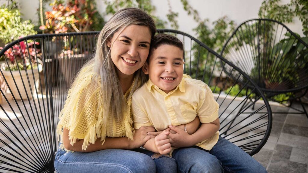 Latino mother and son hugging each other on a patio chair