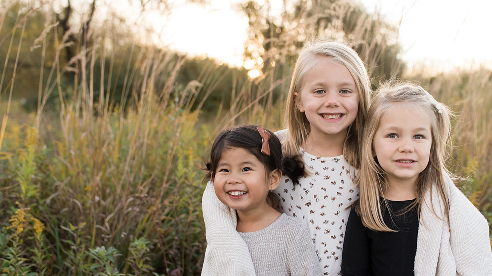 Three sisters smiling in a field together