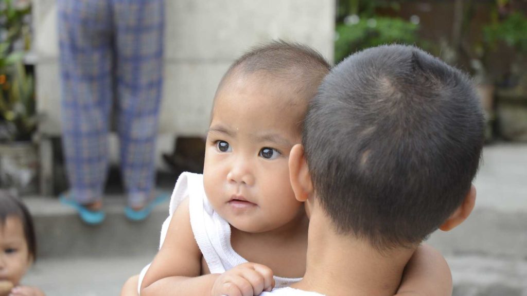 boy holds younger sibling in the Philippines