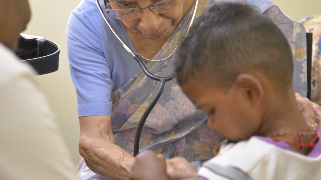 woman checking boys heart with stethoscope