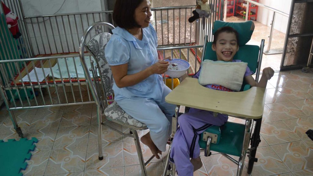 caretaker feeding handicapped girl