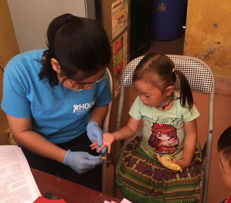 Phuong, a child nutrition program trainer in Vietnam, screens a child for anemia as part of a routine nutrition screening.